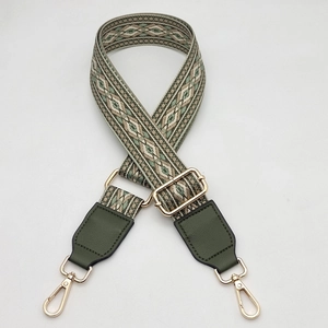 Detail of adjustable geometric strap with olive green leather ends and gold metal buckles