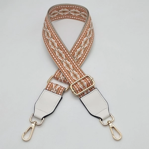 Close-up of geometric woven strap with white leather ends and gold metal hooks