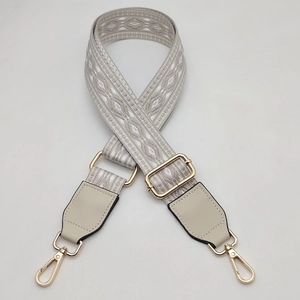 Detail view of adjustable jacquard woven bag strap with golden metal lobster clasps