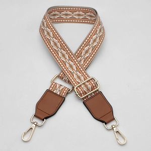Close-up of woven bag strap with geometric patterns, brown leather, and gold hardware