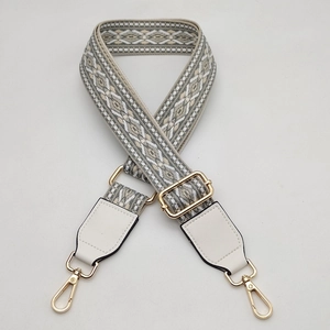 Macro view of woven grey geometric strap with gold metal buckles and white leather ends