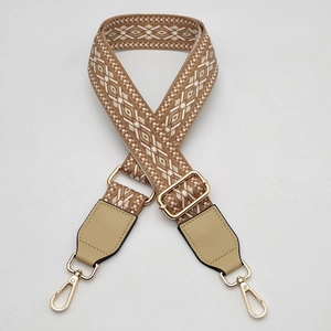 Close-up of geometric pattern jacquard bag strap with golden metal hooks and leather