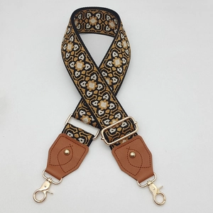 Détail d'une bandoulière tissée géométrique avec crochets dorés et embouts en cuir