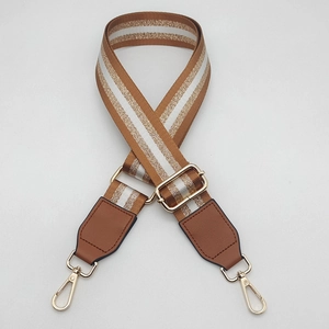 Detail of adjustable wide bag strap featuring brown and gold metallic stripe patterns