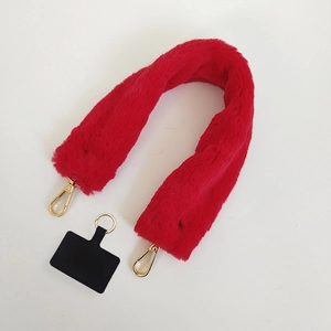 Detail of red plush faux fur bag strap with gold metal lobster clasps and phone tether