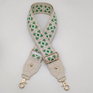 Détail de la bandoulière tissée géométrique verte et beige avec des crochets dorés et cuir