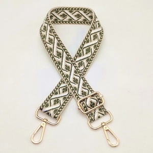 Close-up of jacquard woven strap with green geometric patterns and gold metal hardware