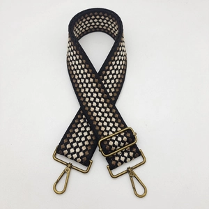 Close-up of geometric embroidered bag strap with vintage bronze metal lobster clasps