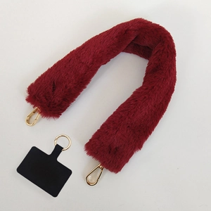 Close-up of plush wine red shoulder strap with golden lobster clasps and phone connector pad