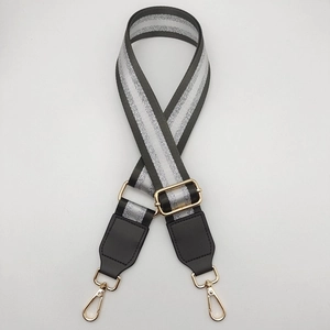 Adjustable silver striped bag strap with black leather ends and gold metal hardware