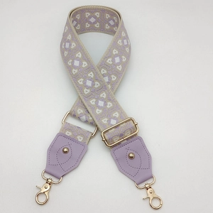 Détail de la sangle jacquard géométrique violette et beige avec quincaillerie dorée et cuir
