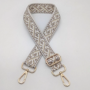 Close-up of jacquard shoulder strap with gold metal buckles and geometric pattern
