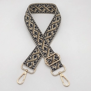 Detail of adjustable wide jacquard bag strap with vintage geometric patterns and gold clips