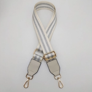 Close-up of adjustable cream woven bag strap with silver glitter stripes and gold hardware