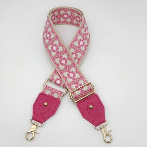 Détail d'une bandoulière jacquard colorée avec attaches en cuir magenta et boucle dorée