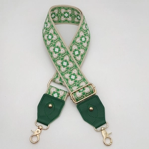 Détail d'une bandoulière tissée géométrique verte avec cuir et crochets dorés