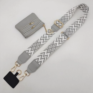 Detailed view of gray patterned crossbody strap with mini pouch and gold hardware hooks