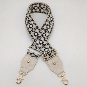 Détail d'une large bandoulière jacquard géométrique avec cuir crème et crochets dorés