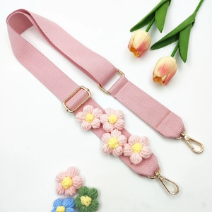 Détails de la bandoulière de sac tricotée rose avec fleurs et mousquetons en métal doré
