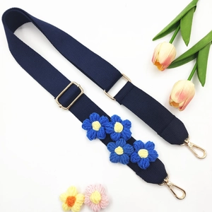 Détail de la bandoulière en tricot à fleurs bleu marine avec ferrures dorées réglables