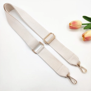 Detail of off-white 3.8cm canvas bag strap with gold lobster clasps and metal buckle
