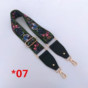 Détail de la bandoulière réglable verte avec motif papillon coloré et crochets dorés