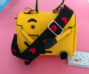 Detail of yellow cartoon shoulder bag featuring red heart embroidery on wide black woven strap