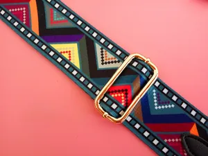 Detail of colorful geometric woven bag strap with golden buckle on pink background