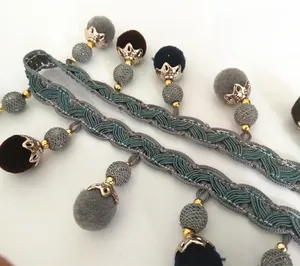 Nahaufnahme des Ethno-Webgurts mit blauen Pompons und goldenen Metallbeschlägen im Detail