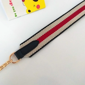 Détail d'une bandoulière tissée avec extrémités en cuir noir et maillons de chaîne dorés