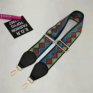 Macro shot of colorful woven guitar-style bag strap with gold metal buckle and leather ends