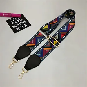 Close-up of colorful geometric woven bag strap with black leather and gold metal hooks
