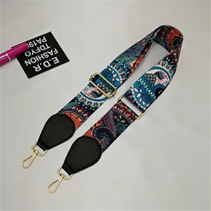 Detail of wide woven strap with paisley pattern and golden metal lobster clasps