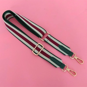 Close-up of adjustable striped canvas bag strap with gold metal hooks and vintage design