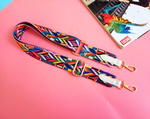 Close-up of bohemian ethnic woven bag strap with colorful geometric patterns and gold clips