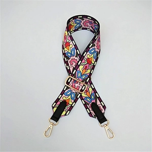 Close-up of ethnic floral wide strap with gold metal lobster clasps and black leather trim