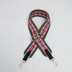 Detail view of ethnic pink geometric woven strap with golden spring hooks and buckle