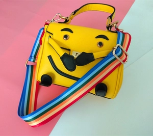 Macro shot of yellow cartoon crossbody bag with colorful rainbow strap and gold hardware