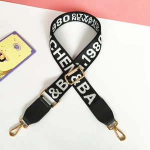 Detail of black woven shoulder strap with white letters and gold metal buckles for bags
