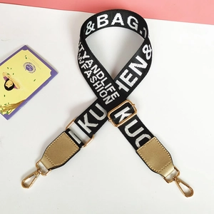 Detail of black and white nylon bag strap with gold metal lobster clasps and text