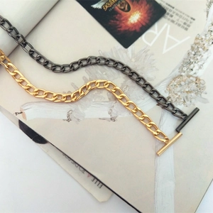 Detailed close-up of thick metal chain straps in bright gold and gunmetal with OT toggle clasps