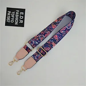 Close-up of ethnic floral wide bag strap with gold metal buckles and pink leather joints