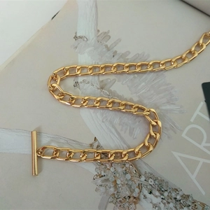 Close-up of golden Cuban chain link accessory with decorative OT clasp on art magazine