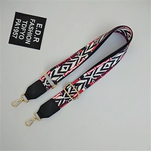 Ethnic geometric woven bag strap with red and black patterns and gold metal buckles