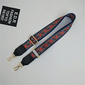 Close-up of adjustable ethnic pattern bag strap with gold metal hooks and leather ends