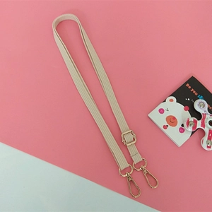 Bandoulière réglable en coton beige avec boucles dorées pour sacs à main sur fond rose
