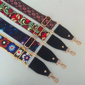 Detail of four colorful patterned nylon bag straps with gold metal hooks and leather ends