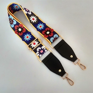 Detail of wide nylon crossbody strap with ethnic floral pattern and gold metal hooks