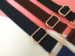 Vue détaillée des bandoulières larges en nylon bleu, marron, noir avec boucles dorées