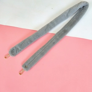 Detail of grey faux fur shoulder strap with golden metal snap hooks for handbags